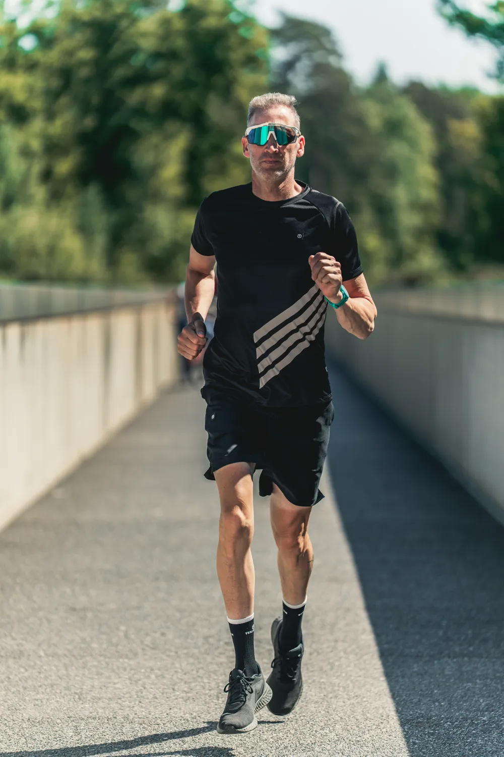Loper in zwart sportshirt op een brug